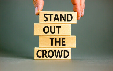 Stand out the crowd symbol. Concept words Stand out the crowd on wooden blocks on beautiful grey...