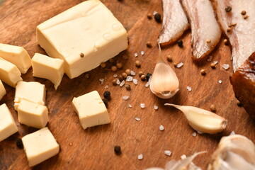 still life of food in a rural style on a dark wood background, sliced cheese and bacon, garlic, salt and pepper, concept of healthy food