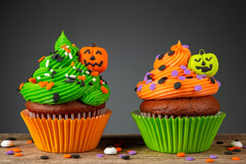 Cupcake on Halloween. Pumpkin Jack o lantern. Dessert on Halloween party. Muffin decorated with colored sprinkles, frosting and Icing shaped pumpkin Jack-o-lantern. Cupcakes on a wooden table.