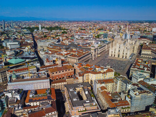 Obraz premium Aerial view of Piazza Duomo in front of the Gothic cathedral in the center. Drone view of the gallery and rooftops during the day. Flight over the city. People in the city. Milan. Italy 2022