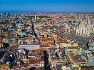 Aerial view of Piazza Duomo in front of the Gothic cathedral in the center. Drone view of the gallery and rooftops during the day. Flight over the city. People in the city. Milan. Italy 2022