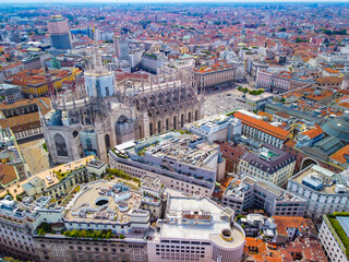 Fototapeta premium Aerial view of Piazza Duomo in front of the Gothic cathedral in the center. Drone view of the gallery and rooftops during the day. Flight over the city. People in the city. Milan. Italy 2022
