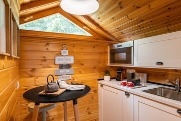Compact kitchen with small round dining table in wooden house. Village life concept.