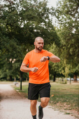 Fototapeta premium Athlete using a smartwatch while running in nature Healthy lifestyle