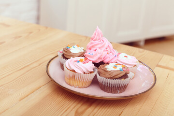 bright cakes with delicate cream on a pink plate stand on a wooden table