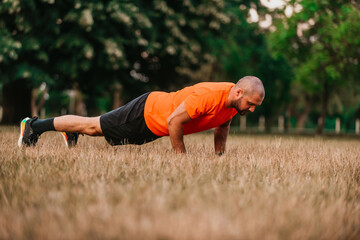 Young man working out doing push-ups in park as he warms up for his daily workout or jog