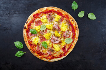 Traditional Italian pizza Hawaii with ham, pineapple and mozzarella served as top view on an old rustic board with text free space