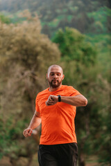 Fototapeta premium Athlete using a smartwatch while running in nature Healthy lifestyle