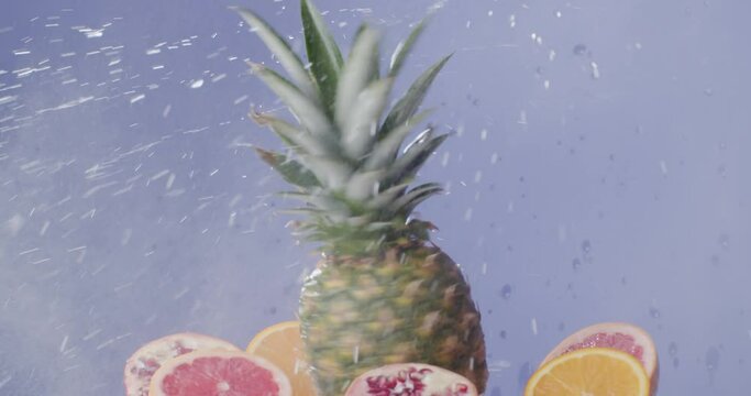 Spinning pineapple splashing water with oranges beside it