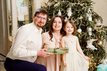 happy family with box of gift by Christmas tree. tradition giving gifts
