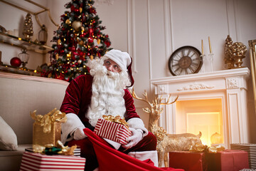 Santa Claus puts presents in his big red bag to wish the children a Merry Christmas.