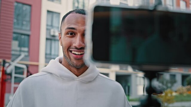 African biracial latin sportsman trainer handsome blogger put mobile phone on tripod record video vlog from sports ground training online promoting fitness exercises tutorial blog of healthy lifestyle