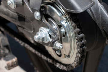 Detail of a motorcycle wheel, swingarm, sprocket and rear drive chain transmitting engine power