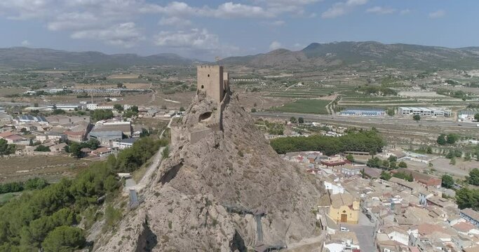 Castillo sobre un risco rocoso rodeado de bosques y encima de un pueblo medieval a vista de dron no etalonado