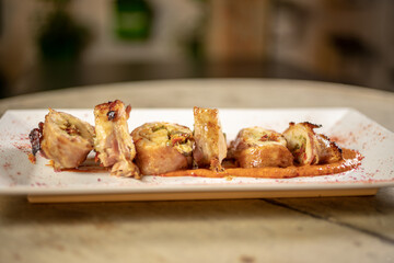 Different cuts of meat, chicken and pork on a white plate on a light wooden background
