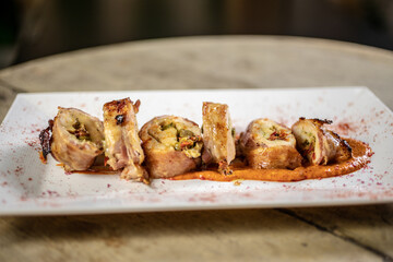Different cuts of meat, chicken and pork on a white plate on a light wooden background
