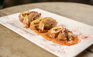 Different cuts of meat, chicken and pork on a white plate on a light wooden background
