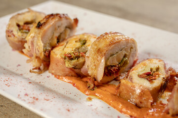 Different cuts of meat, chicken and pork on a white plate on a light wooden background
