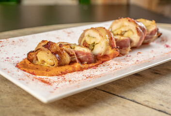 Different cuts of meat, chicken and pork on a white plate on a light wooden background
