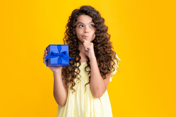 Child with gift present box on isolated studio background. Gifting for kids birthday. Thinking...
