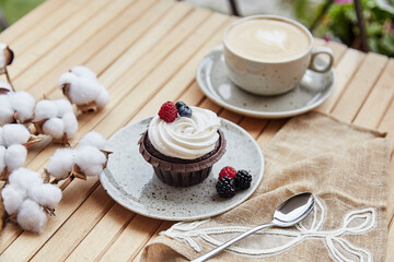 Natural gluten and sugar free berries cupcake and cup of coffee. Cotton decoration. Cozy lunch at the terrace
