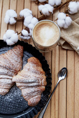 Aesthetic breakfast outside - fresh french croissants, cup of latte at the terrace. Autumn coziness. Cotton decoration. Pastel background