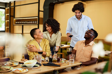 A multicultural friends are drinking wine in a restaurant at the dinner table.