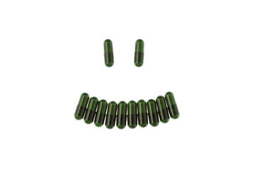 Antidepressants. Green Herb capsules with plant extract in shape smile, isolated on white...