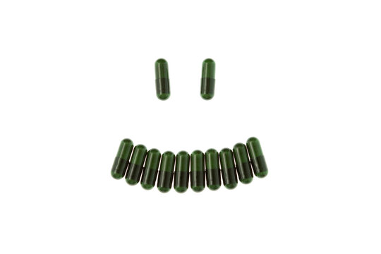 Antidepressants. Green Herb capsules with plant extract in shape smile, isolated on white background. Nutritional Supplement. Vitamin Pill. Herbal Medicine
