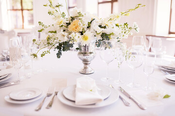A table decorated with white flowers for seating guests at a wedding banquet. Selective focus.