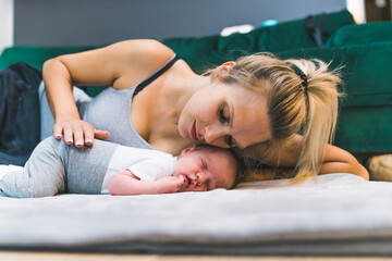 Adorable newborn baby boy with cute brown hair, sleeping peacefully on his stomach on a bed at home...