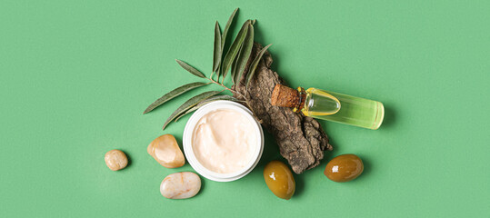Fototapeta na wymiar Composition with jar of natural olive cream and oil on green background