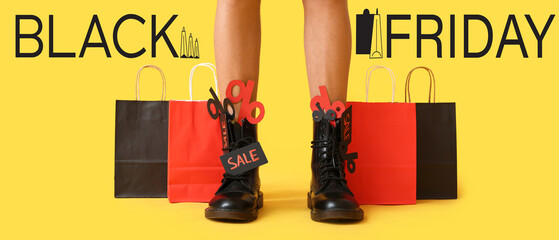 Legs of young woman with shopping bags on yellow background. Black Friday sale