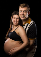 Fototapeta na wymiar Mother and father to-be embrace each other and the baby bump.