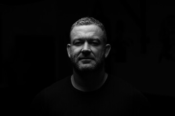 Adults male in darkness and looking into camera.