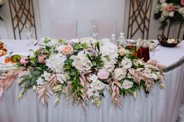 Beautiful multi-colored flowers hang on a table with a white sheet and food. Wedding decorations, photography.