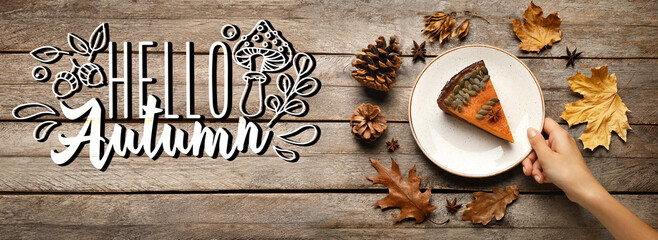 Female hand, plate with piece of delicious pumpkin pie and dry leaves on wooden background. Hello,...