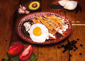 Chilaquiles con huevo y milanesa desayuno mexicano en mesa de madera con ingredientes frescos 