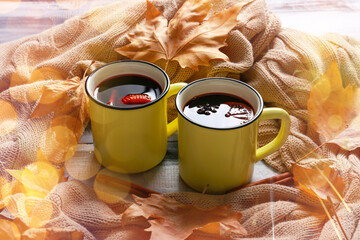 Metal mugs of delicious mulled wine, warm plaid and autumn leaves on wooden table
