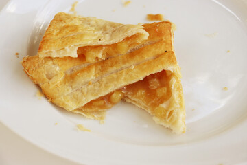 Opened Apple turnover, croissant, cake. pastry, bakery with apple cinnamon filling laying on the white plate. Close-up. Copy space.