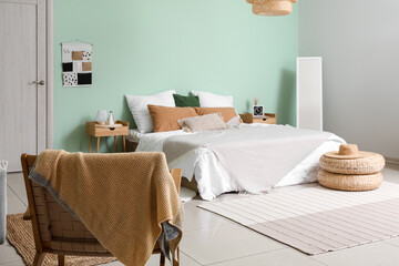 Interior of cozy bedroom with rattan poufs, mirror and armchair