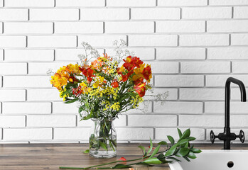 Vase with bouquet of alstroemeria flowers on kitchen counter near sink