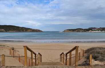 Escadas em madeira de aceso a uma praia com alinhamento com a entrada de uma enseada no mar