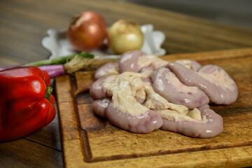 Cow bowels presented on a wooden board with ingredients, ready to grill