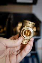 brass hydraulic fitting kept in your hand (selective focus, blur)