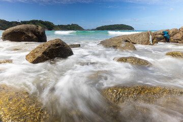 Long exposure of waves during sunny day at the seashore on blue sky background
