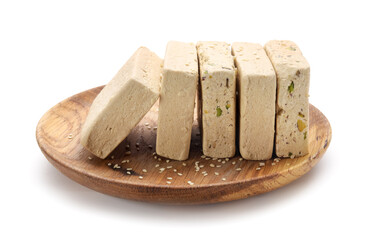 Wooden plate with pieces of tasty sesame halva on white background