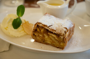 Austrian sweet dessert, portion of apple strudel with whippen cream and hot vanilla sauce served in old bakery cafe in Vienna, Austria