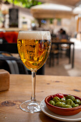 Glass of cold beer in Spanish outdoor cafe, tapas bowl with green olives