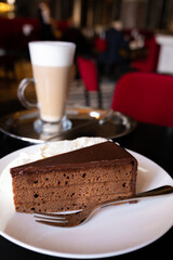 Piece of famous Sachertorte chocolate cake with apricot jam of Austrian origin served with whipped cream